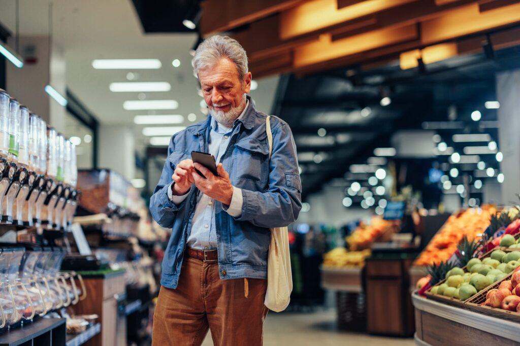 Mature man using smartphone while shopping